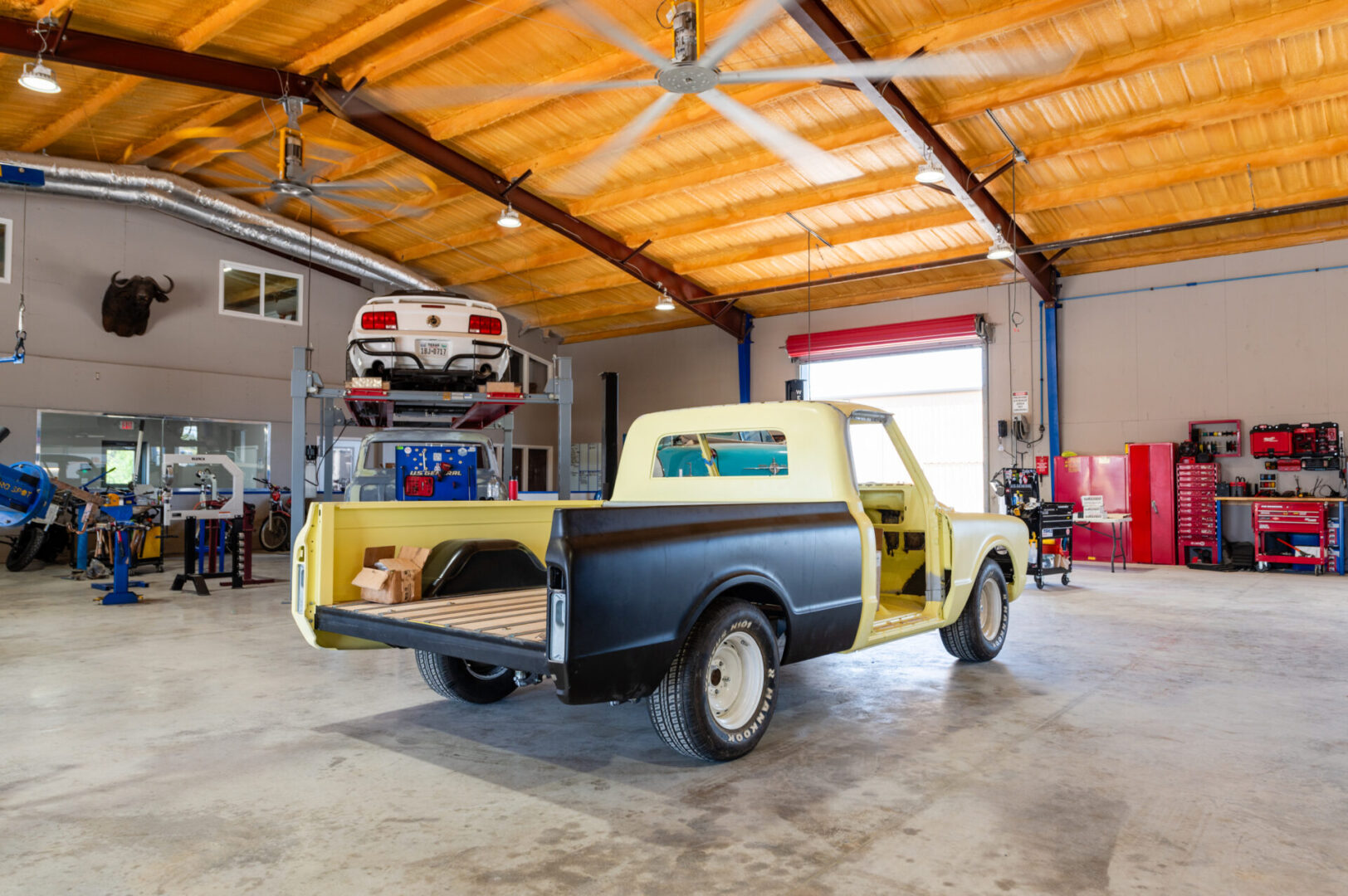 A truck in the garage with two cars parked on top of it.