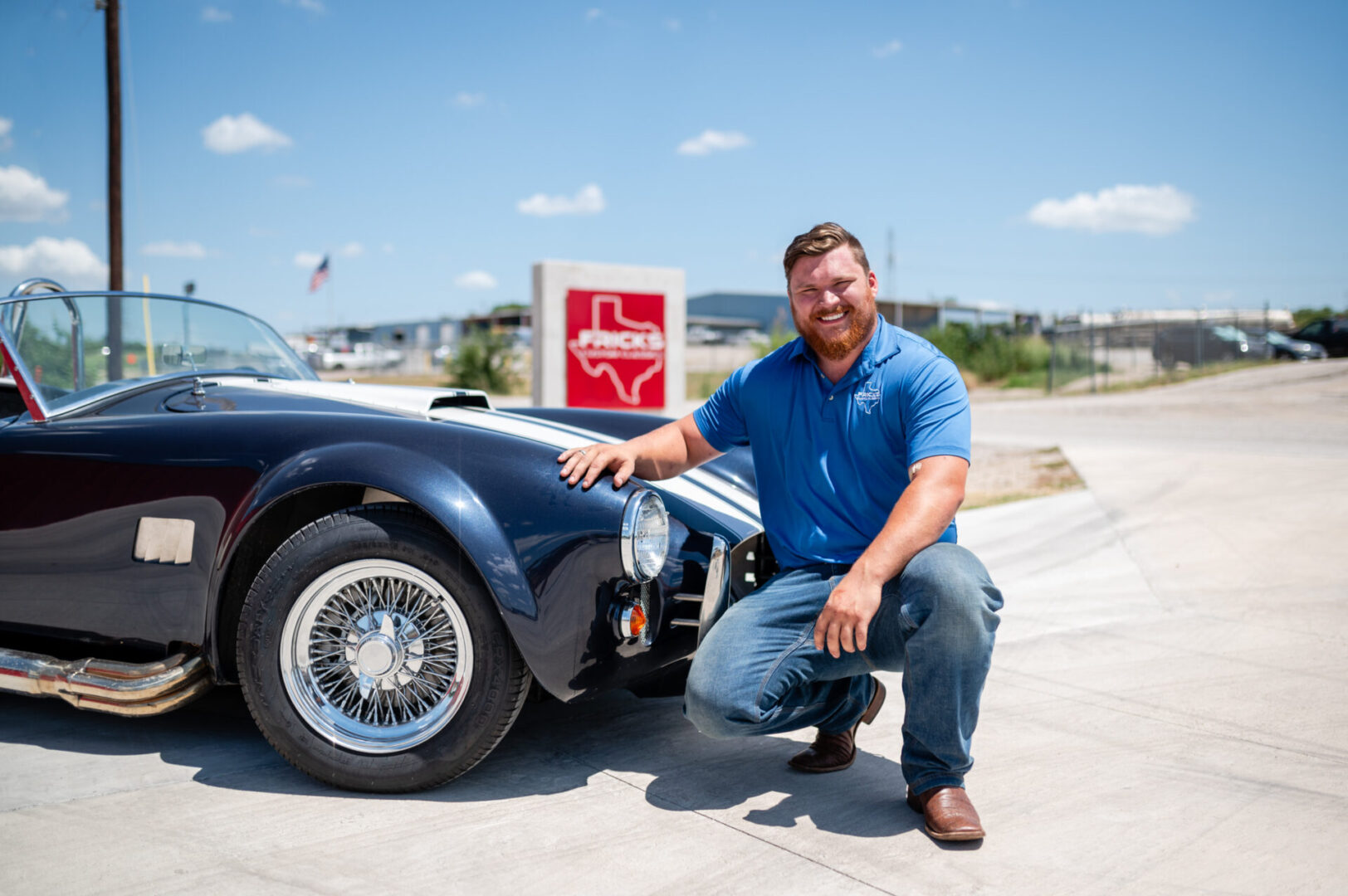 A man kneeling next to an old car.