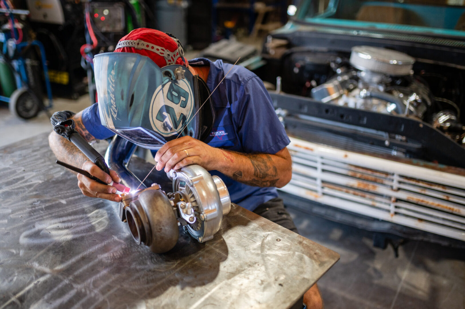 A man welding in the shop with an industrial machine.