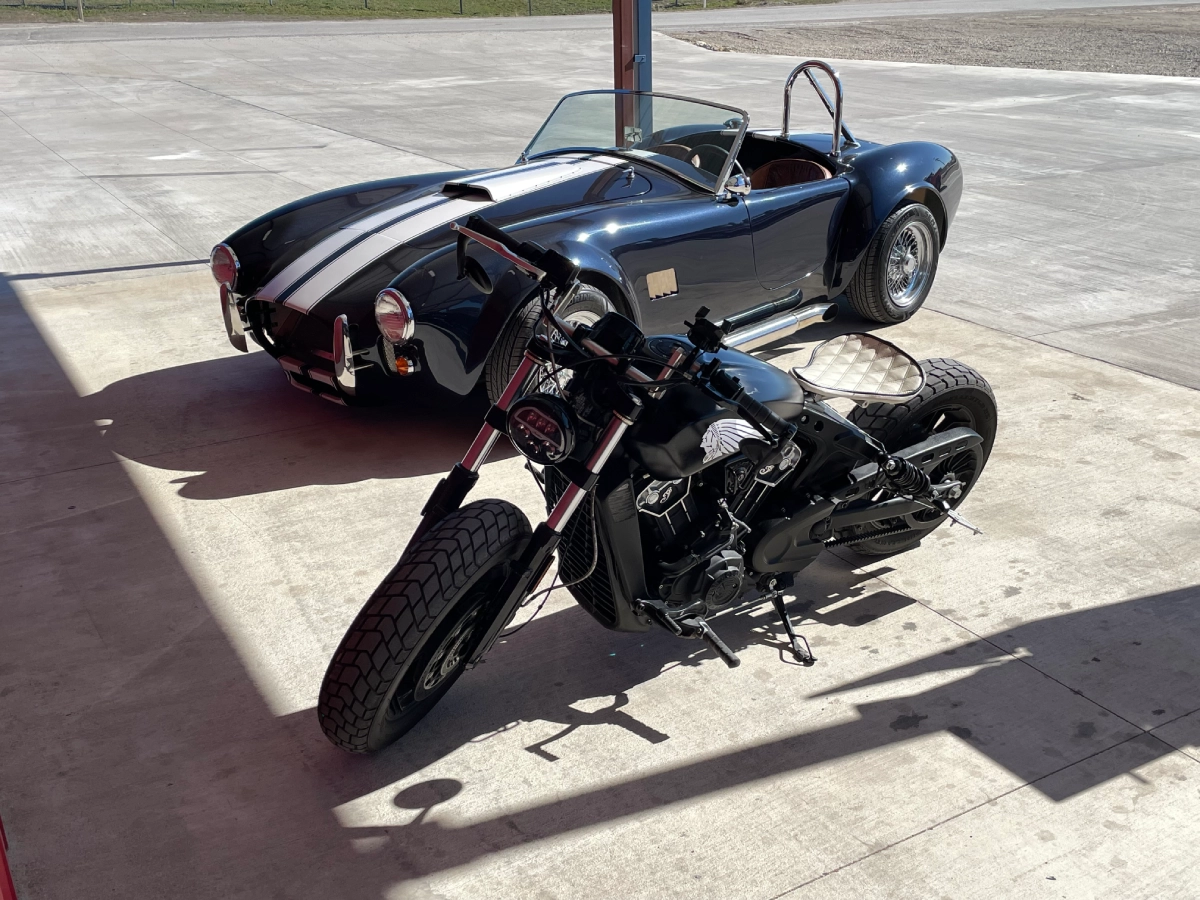 A motorcycle and car parked on the side of a road.