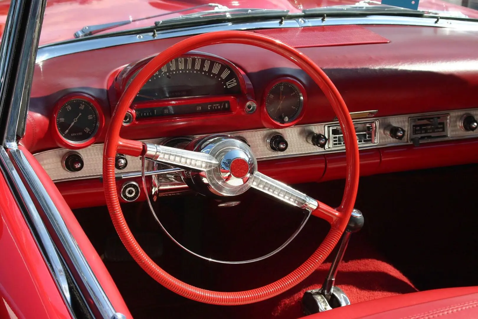 A red car with the steering wheel turned to the left.